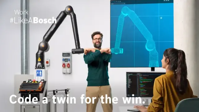 Twee medewerkers spelen aan een voetbaltafel met een Bosch Rexroth APAS assistentierobot.